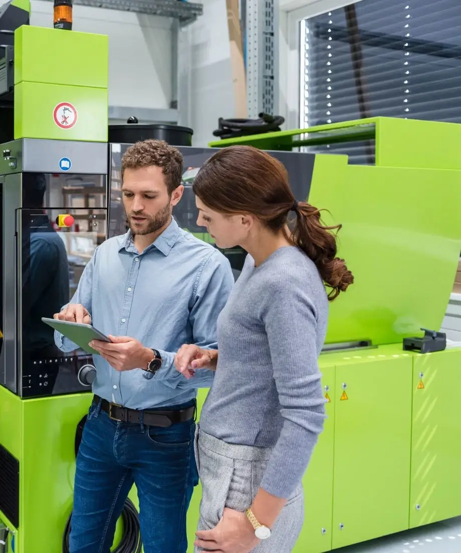 Dwie osoby podczas pracy, rozmawiające przy wtryskarce